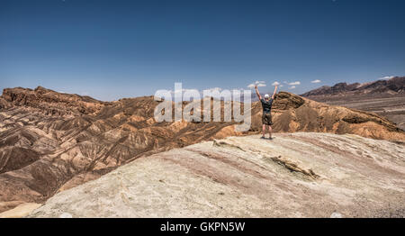 Death Valley und ein glückliche Wanderer stehend auf der Felge mit Armen hochgezogen. Sieger, Leistung und Erfolg-Konzept in der Natur. Stockfoto