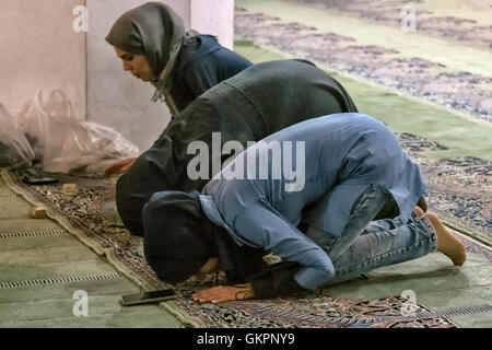 Junge Frauen tragen Hijab beten Richtung Mekka in der Schah-Moschee in Isfahan, Iran.  Sie haben Gebet Steinen oder Salat für ihre Stirnen und auch Handys. Stockfoto