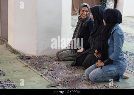 Junge Iranerinnen tragen Hijab Knien in der Schah-Moschee in Isfahan, Iran, um mit ihren Handys und Gebet Steinen (Salate) zu beten. Shah Moschee, auch bekannt als Imam-Moschee, nach der islamischen Revolution von 1979 im Iran und in Jaame umbenannt "Abbasi Moschee ist eine Moschee in Isfahan, Iran, stehend in der Südseite des Naghsh-e Jahan Quadrat. Stockfoto