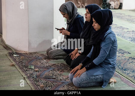 Junge Iranerinnen tragen Hijab Knien in der Schah-Moschee in Isfahan, Iran, um mit ihren Handys und Gebet Steinen (Salate) zu beten. Shah Moschee, auch bekannt als Imam-Moschee, nach der islamischen Revolution von 1979 im Iran und in Jaame umbenannt "Abbasi Moschee ist eine Moschee in Isfahan, Iran, stehend in der Südseite des Naghsh-e Jahan Quadrat. Stockfoto