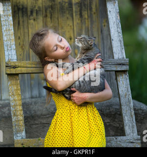 Lustige kleine Mädchen eine Katze im Arm halten. Stockfoto