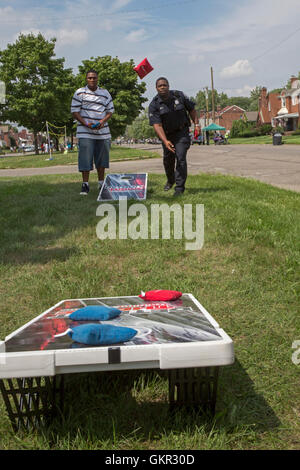 Detroit, Michigan - Nachbarschaft Gruppen halten ein Sommer Street fair. Ein Polizist schließt sich Community-Mitglieder in Cornhole spielen. Stockfoto