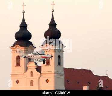 TIHANY, Ungarn - 17. AUGUST: Ein Flugzeug fliegt vor der Abtei über das Dorf am 17. August 2016 in Tihany, Ungarn. Stockfoto