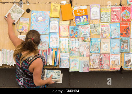 Ein Buchhändler legt ihre Bücher auf dem Buchmarkt Southbank Centre in London, als das Land wird sich durch das Wetter in eine Nord-Süd-Gefälle - aufgeteilt werden wie der Süden brutzelt und Teile des Nordens auf Wasseralarm bleiben. Stockfoto