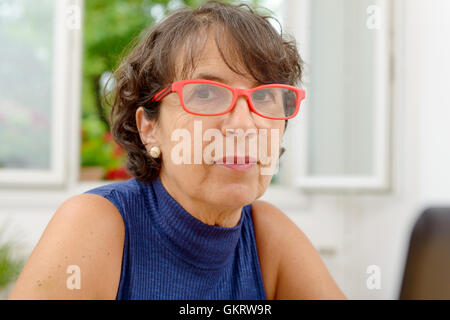 Porträt einer schönen reifen Frau mit roten Brille Stockfoto