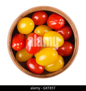 Cocktailtomaten in einer Holzschale auf weißem Hintergrund. Gelbe und rote Reife Früchte von Solanum Lycopersicum, eine Art Beerenfrucht. Stockfoto