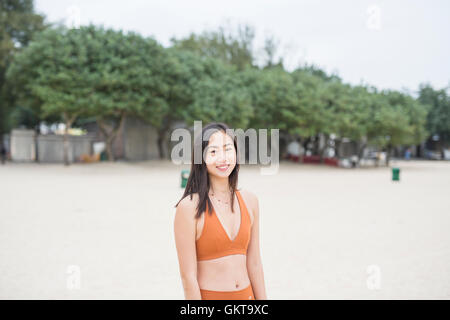 Chinesische Frau in Orange Yoga am Strand zu tun. Stockfoto