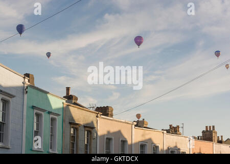 Heißluftballons pass über den bunten Terrassen des Cliftonwood in Brostol während der jährlichen Balloon Fiesta. Stockfoto