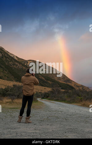 Menschen nehmen Foto von Regenbogen über Berg in der Nähe von Lake Pearson, Neuseeland Stockfoto