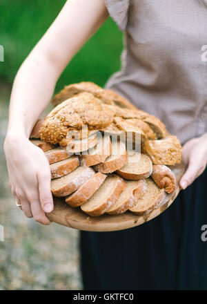 Frau hält in der hand ein Holztablett mit dem Schnitt Brot Stockfoto