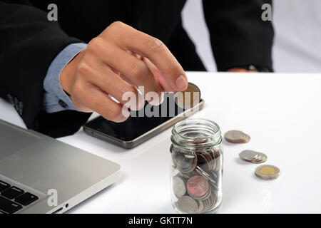 Geschäftsmann, goldene Münzen in der Flasche setzen. Konzept der Investitionen. Stockfoto