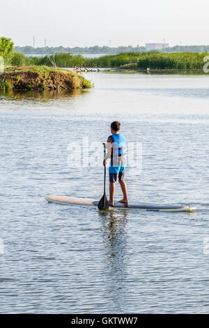 Ein 12-14 Jahre alten kaukasischen junge auf einem Stand up Paddle Board auf dem North Canadian River in Oklahoma, USA. Stockfoto