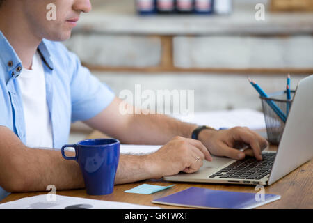 Junger Geschäftsmann arbeiten am Laptop im home-Office Interior im Dachboden. Gut aussehend ernsthaften Mann mit Laptop im Holz sitzen Stockfoto