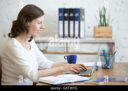 Porträt des jungen Business-Frau mit Laptop im home-Office Interior im Dachboden. Glücklich casual Büro sitzenden Stockfoto