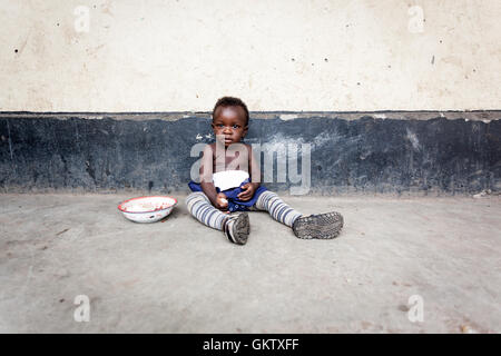 Ein junges Mädchen oder Kleinkind isst innerhalb einer Schule in uganda Stockfoto