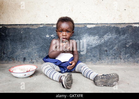 Ein junges Mädchen oder Kleinkind isst innerhalb einer Schule in uganda Stockfoto