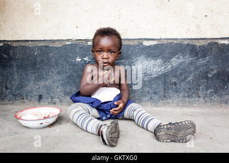 Ein junges Mädchen oder Kleinkind isst innerhalb einer Schule in uganda Stockfoto