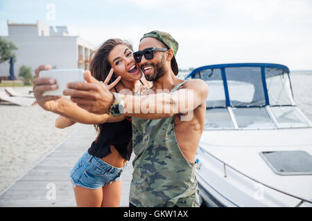 Porträt von ein glückliches Paar, Selfie Foto auf Smartphone im Freien am See pier Stockfoto