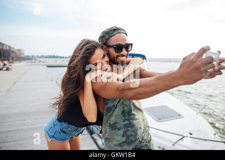 Porträt von ein glückliches Paar, Selfie Foto auf Smartphone im Freien am See pier Stockfoto