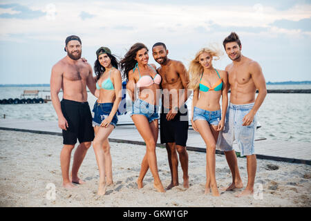 Gruppe von fröhlich glücklich jungen Freunden am Strand stehen und Lächeln Stockfoto