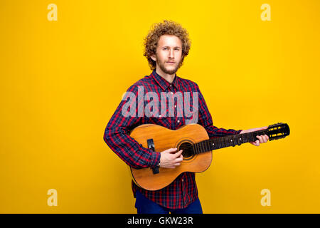 Curly-behaarte Mann in in kariertes Hemd, Gitarre spielen Stockfoto