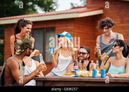 Gruppe von fröhlichen jungen Menschen tranken Bier und Erfrischungsgetränke und lachten im freien Stockfoto