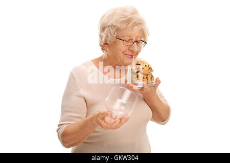 Alte Frau riechen einen offenen Tiegels von Cookies isoliert auf weißem Hintergrund Stockfoto