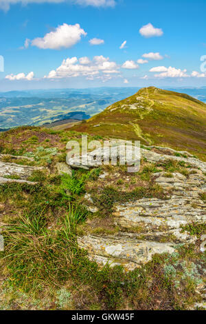 Landschaft mit Steinen unter dem Rasen am Hang in der Nähe von den Weg gehen, Berggipfel unter blauem Himmel mit Wolken Stockfoto