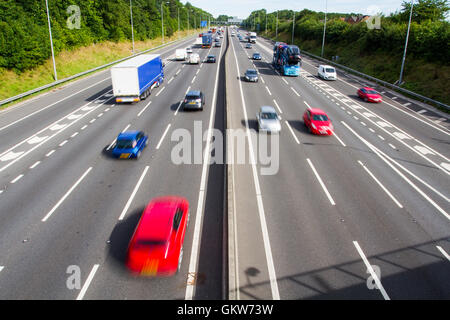 Blick von einer Brücke auf die beiden Richtungsfahrbahnen einer stark frequentierten Autobahn oder Landstraße voll von schnell fließenden Verkehrs. Stockfoto