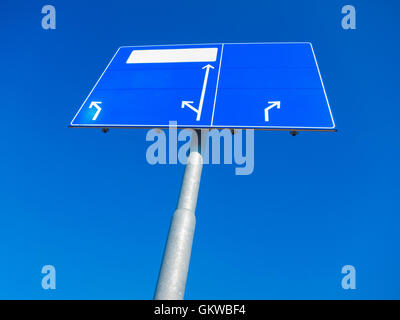 Leere blaue Wegweiser zeigen in unterschiedliche Richtungen gegen blauen Himmel Stockfoto