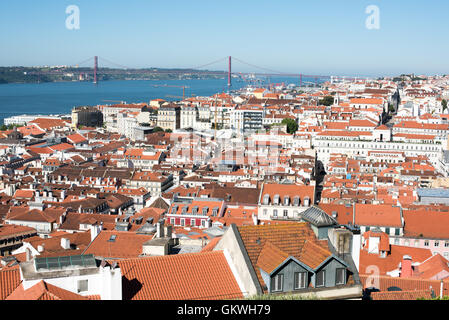 Lissabon Stadtbild Tagus Fluss 25 de Abril Brücke Blick vom Schloss Sao Jorge Lissabon Portugal / LISSABON, Portugal - Ein Panoramablick von der Stadtmauer Castelo de São Jorge nach Westen nimmt die Stadtlandschaft von Lissabon, den breiten Fluss Tejo und die Hängebrücke Ponte 25 de Abril auf. Die Burg befindet sich auf dem höchsten Hügel im Zentrum von Lissabon, oberhalb des Alfama-Viertels, und entstand im elften und zwölften Jahrhundert als maurischer alcáçova, bevor sie nach 1255 etwa drei Jahrhunderte lang als königlicher Palast portugiesischer Könige diente. Die Ponte 25 de Abril erstreckt sich über den Tejo, der Lissabon mit Almada verbindet; Stockfoto