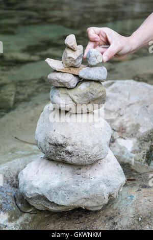 Ausgleich in den Bach La Blanque, einem Nebenfluss des Sals Stein. Setzen von Steinen in einem Haufen entlang Flussbett. Aude, Südfrankreich. Stockfoto