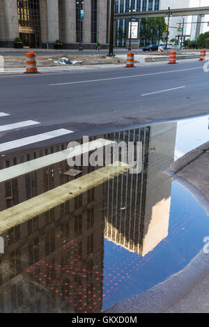 Am Morgen nach einer Regennacht. Straße mit einem Zebrastreifen und eine Pfütze spiegelt die Wolkenkratzer in der Innenstadt von Detroit, USA Stockfoto