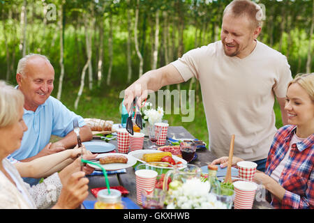 Junger Mann mit Wurst, Reife Frau mit Abendessen Stockfoto