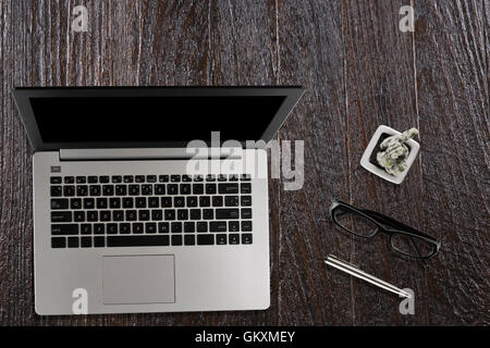 Laptop-Computer, schwarze Brille, Kaktus Topf und Stift auf Holz Schreibtisch - Draufsicht Stockfoto