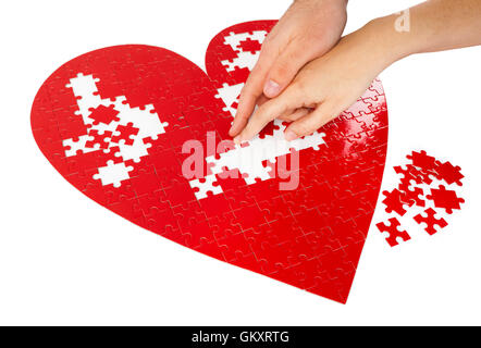 Junges Paar Montage ein rotes puzzle Herzform auf weißem Hintergrund. Stockfoto