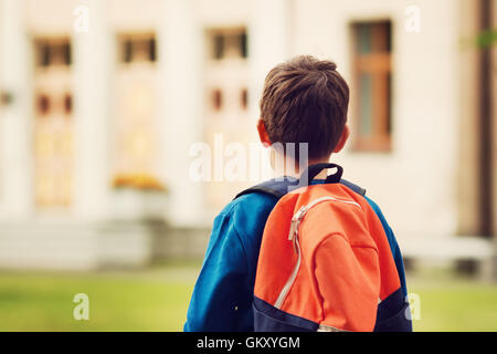 Junge mit Rucksack infront von einem Schulgebäude Stockfoto