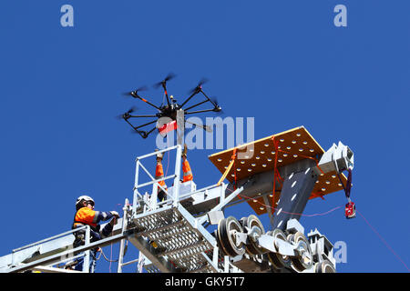 El Alto, Bolivien, 23. August 2016. Ein Techniker erreicht für eine Drohne, die trägt ein synthetisches Lichtkabel zwischen den Masten einer neuen Seilbahn / Gondel lift derzeit im Bau zwischen dem Rio Seco und La Ceja in El Alto. Dies ist der erste Teil des Prozesses, das endgültige Stahlseil zu installieren, das Gondeln tragen wird. Die Seilbahn ist Teil einer zweiten Phase der Seilbahn-Linien, die Teil eines ehrgeizigen Projekts um Verkehrsstaus zu lindern sind. 3 Routen aus der ersten Phase sind bereits zwischen den Städten La Paz und El Alto in Betrieb. Bildnachweis: James Brunker / Alamy Live News Stockfoto