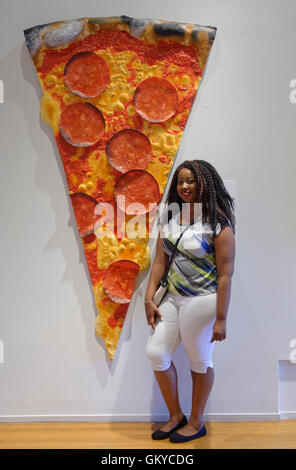 Roslyn Harbor, New York, USA. 23. August 2016. JESSICA von Long Island, stellt neben Kunstwerk "Pizza" des Künstlers Peter Anton (geb. 1963, American) Mixed-Media Slice Pizza mit Peperoni-Scheiben, Schmaus für die Augen-Ausstellung mit Schwerpunkt auf Lebensmittel und Speisen in der Kunst, im Nassau County Museum of Art in Long Island. Bildnachweis: Ann E Parry/Alamy Live-Nachrichten Stockfoto