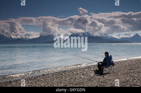 Mann sitzt auf einem Strand Angeln in Homer, Alaska Stockfoto