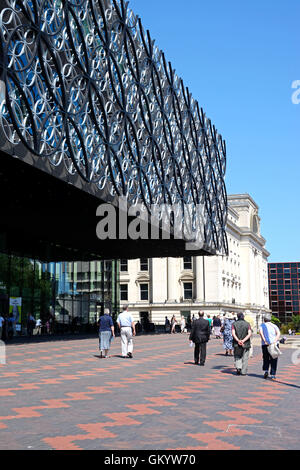 Menschen zu Fuß vorbei an der Library of Birmingham in Richtung Baskerville Haus in Centenary Square, Birmingham, England, Vereinigtes Königreich, Europa. Stockfoto