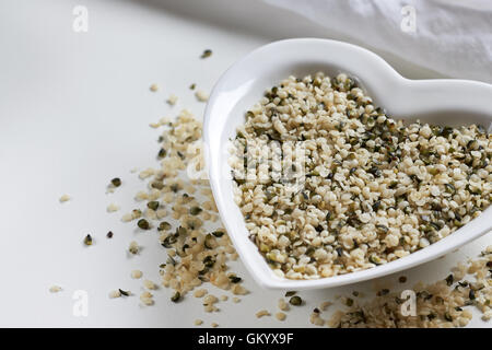 Hanfsamen in Herz Form Keramikschale auf weißem Hintergrund. Textfreiraum Stockfoto