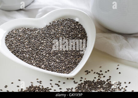 Chia-Samen im Herzen geformt Keramikschale auf weißem Hintergrund Stockfoto