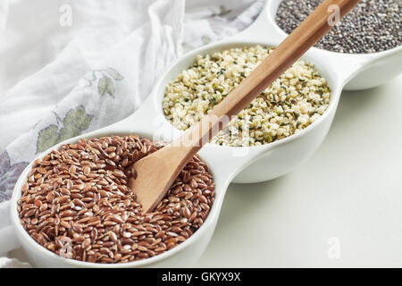 Flachs, Hanf und Chia Samen in Schüssel auf weißem Hintergrund. Vegane Quellen von Omega-3 Stockfoto