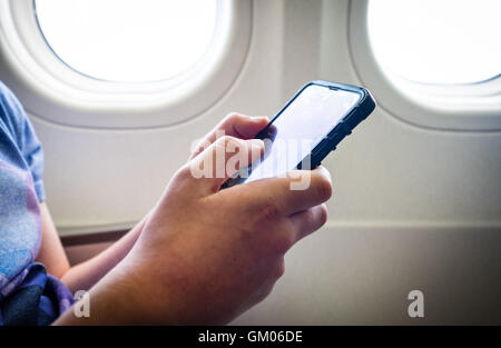 Ein Teenager mit seinem Mobiltelefon während des Fluges auf einer Ebene
