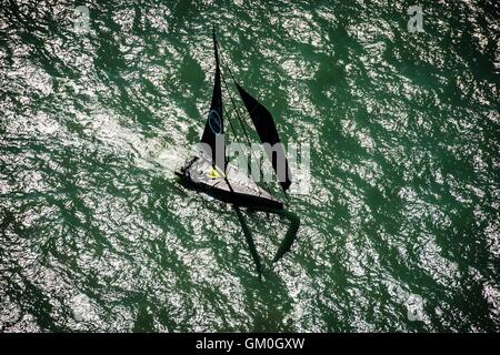 Eine Rennyacht segelt vor der Küste der Isle Of Wight im Solent, da Teile des Landes für heißes Wetter gesetzt werden. Stockfoto