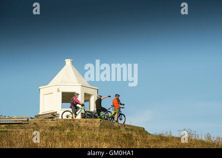 Drei Mountainbiker stehen neben der weißen Suche aufbauend auf Toip Towan Landzunge in Newquay, Cornwall. Stockfoto
