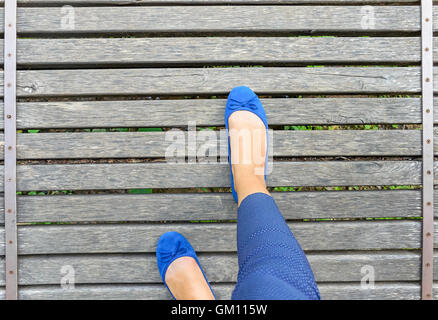 Füße in Schuhen auf einer Holzbrücke. Close-up. Ansicht von oben. Stockfoto