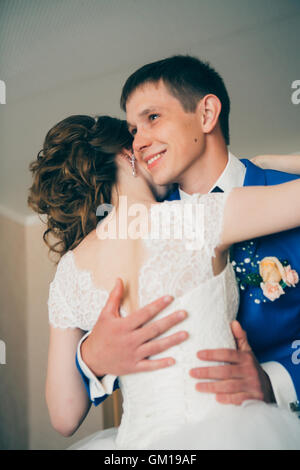junge Braut und Bräutigam in den Hintergrund zu Hause umarmen. Stockfoto