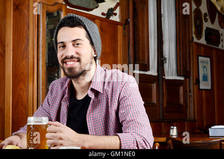 Porträt des Jünglings Latein Bier in einer Bar trinken. Im Innenbereich. Stockfoto